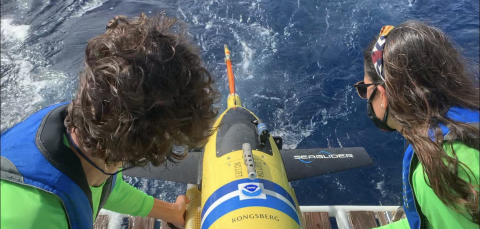 Two ocean researchers release an underwater glider into the ocean.